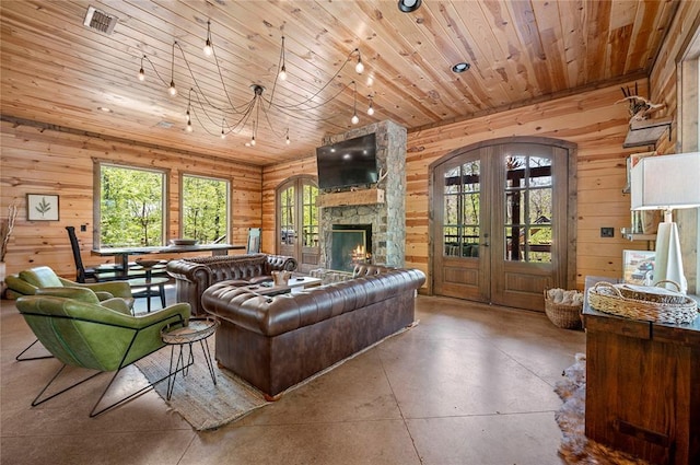 living room featuring wooden ceiling, wood walls, visible vents, finished concrete flooring, and french doors