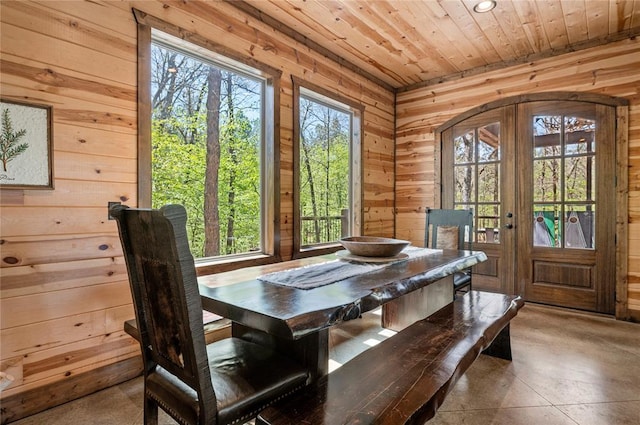 dining room with arched walkways, french doors, wooden ceiling, and wooden walls