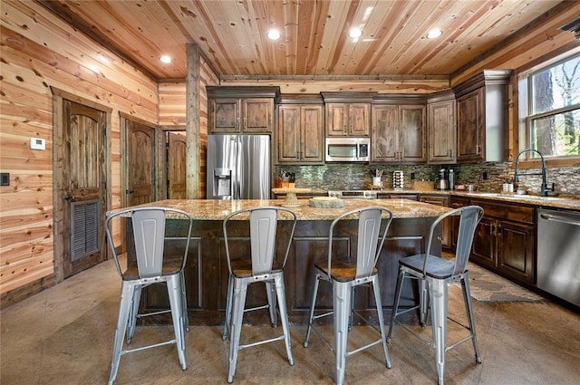 kitchen with backsplash, appliances with stainless steel finishes, wood ceiling, a kitchen island, and a sink