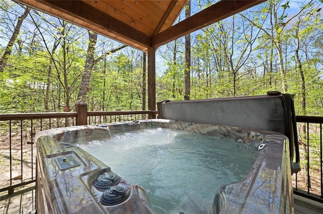 wooden terrace with a hot tub and a forest view