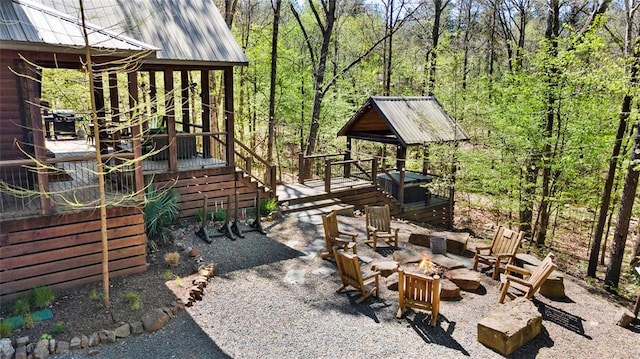 view of yard with a patio area, an outdoor fire pit, a wooded view, and a wooden deck