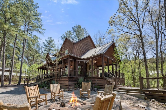 back of property featuring a deck, metal roof, a fire pit, and stairs