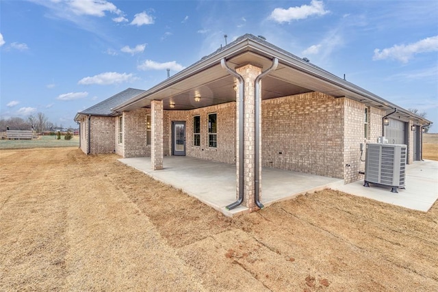 back of property featuring a patio area, brick siding, and central AC unit