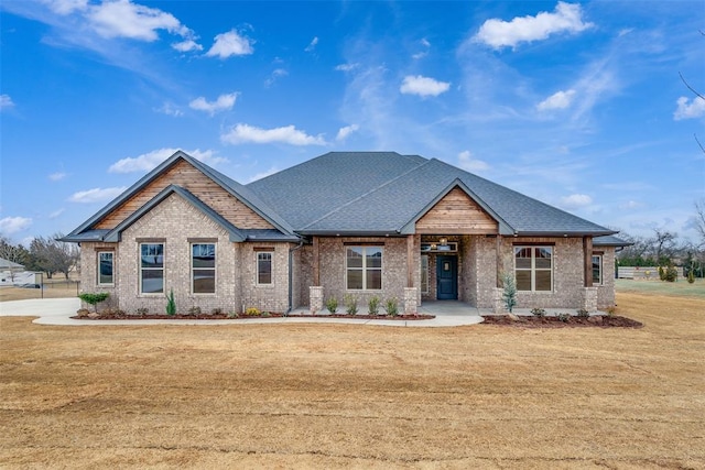 craftsman inspired home featuring brick siding, roof with shingles, and a front yard