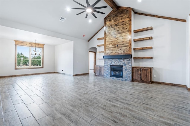 unfurnished living room with beam ceiling, visible vents, wood finished floors, and a stone fireplace