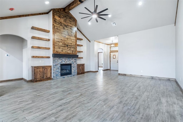 unfurnished living room with arched walkways, ceiling fan, a stone fireplace, and visible vents