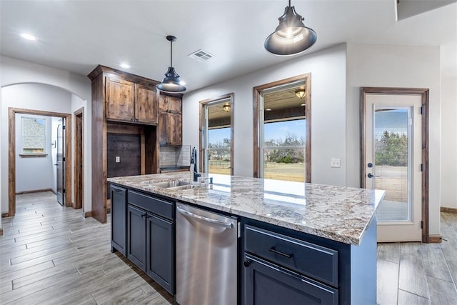 kitchen featuring arched walkways, decorative backsplash, hanging light fixtures, light wood-style floors, and a sink