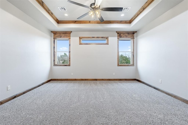 carpeted empty room featuring a raised ceiling, visible vents, crown molding, and baseboards