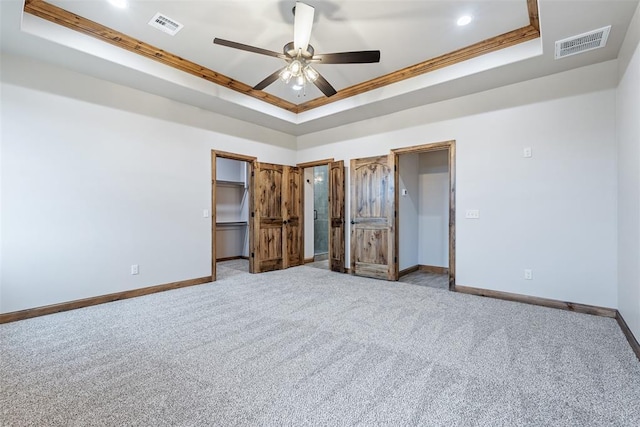 unfurnished bedroom with a tray ceiling, visible vents, and baseboards