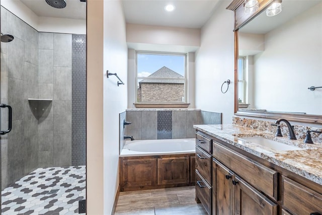 full bathroom featuring a stall shower, a healthy amount of sunlight, a garden tub, and vanity