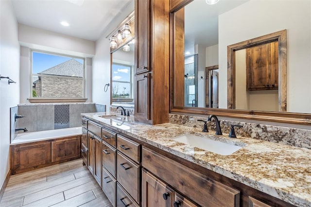 bathroom with a garden tub, double vanity, wood finish floors, and a sink