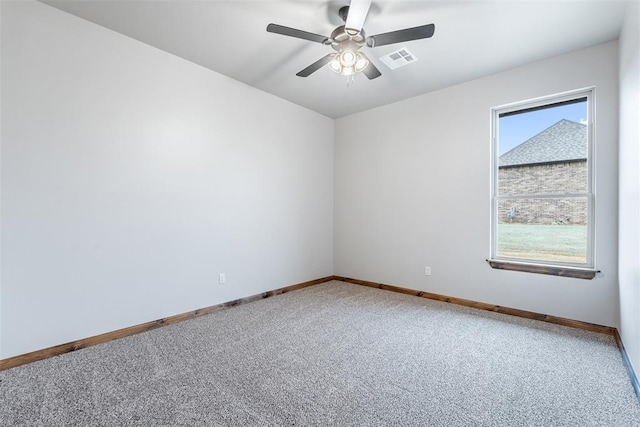 carpeted spare room featuring a ceiling fan, visible vents, and baseboards