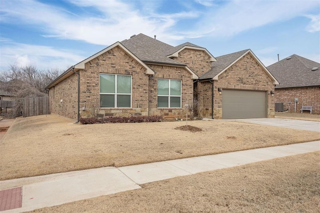 single story home with brick siding, a shingled roof, fence, concrete driveway, and an attached garage