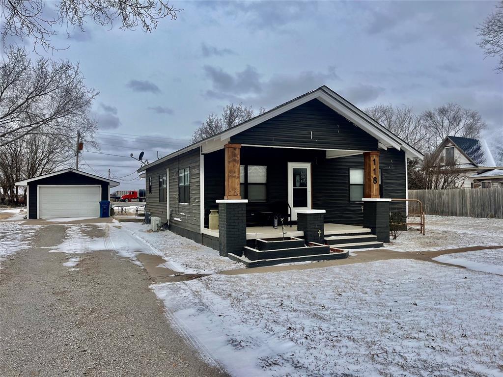 bungalow featuring a detached garage, fence, a porch, and an outdoor structure