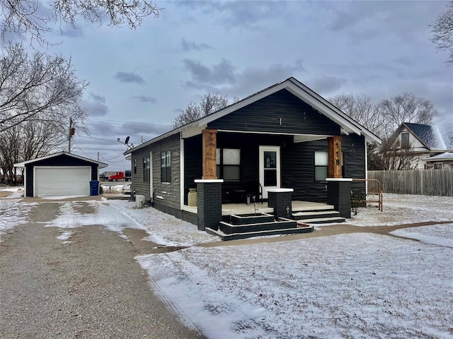 bungalow featuring a detached garage, fence, a porch, and an outdoor structure