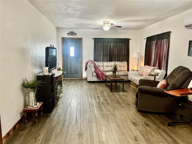 living room featuring a ceiling fan, a textured ceiling, baseboards, and wood finished floors