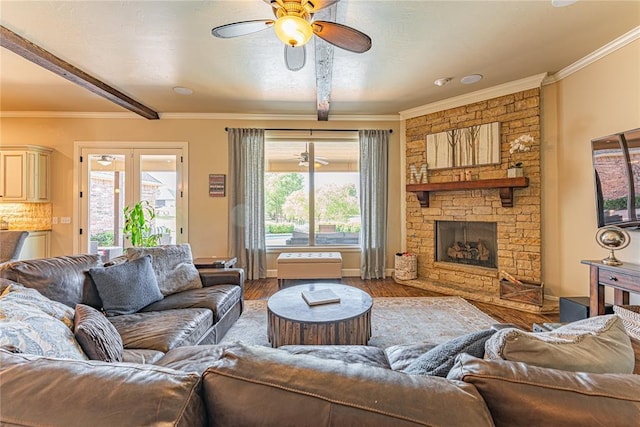 living area with a ceiling fan, wood finished floors, a wealth of natural light, and beamed ceiling