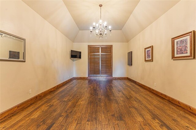 empty room with an inviting chandelier, baseboards, wood finished floors, and lofted ceiling