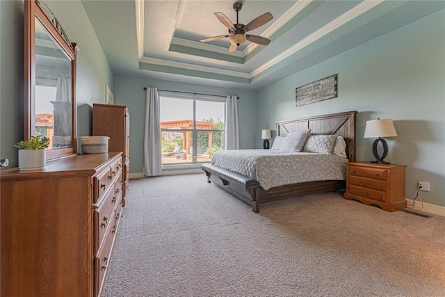 bedroom with ornamental molding, baseboards, light colored carpet, a tray ceiling, and a ceiling fan