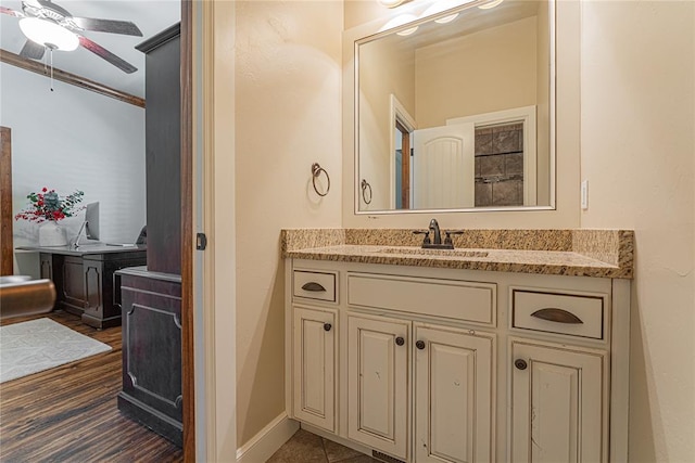 bathroom featuring vanity, baseboards, a ceiling fan, and wood finished floors