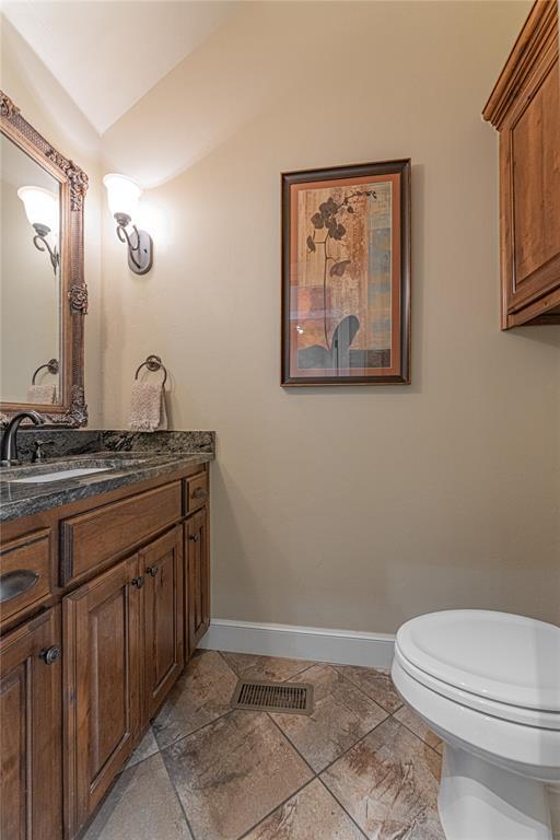 bathroom featuring vanity, toilet, baseboards, lofted ceiling, and visible vents