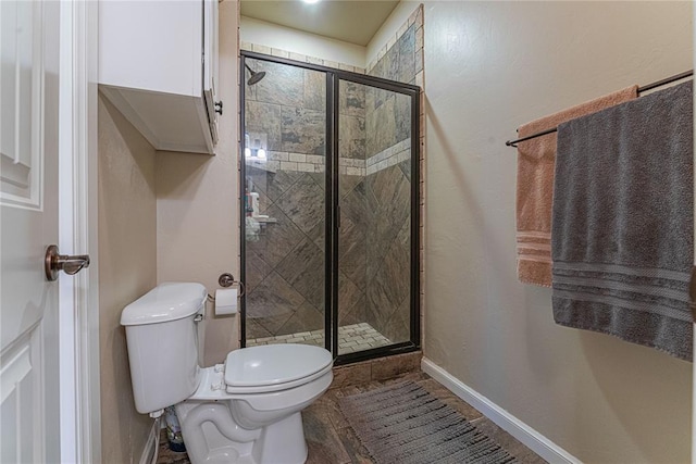 bathroom with toilet, baseboards, and a stall shower