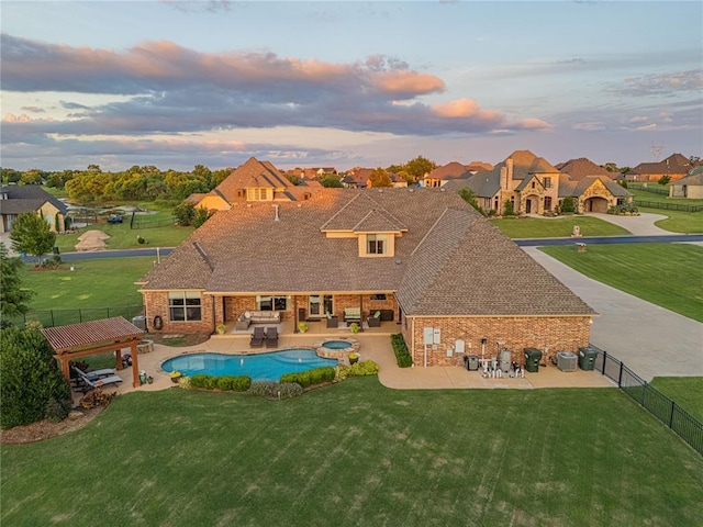 pool at dusk featuring a yard, a fenced backyard, and a patio area