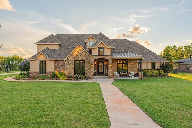 view of front of house with fence, a front lawn, stone siding, and stucco siding
