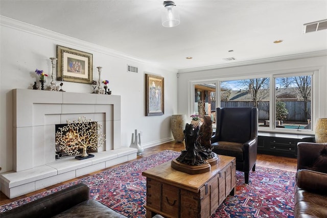 living room featuring visible vents, wood finished floors, baseboards, and ornamental molding