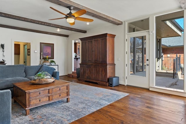 living area featuring beam ceiling, baseboards, a ceiling fan, and wood finished floors