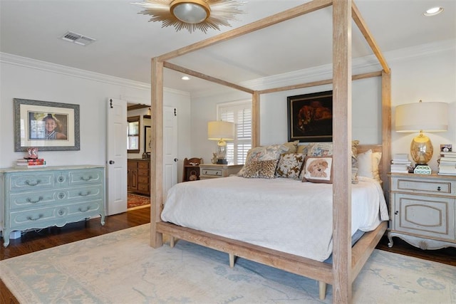 bedroom with dark wood-type flooring, connected bathroom, visible vents, and ornamental molding