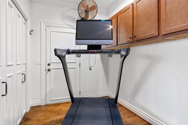 exercise area with crown molding, baseboards, and wood finished floors