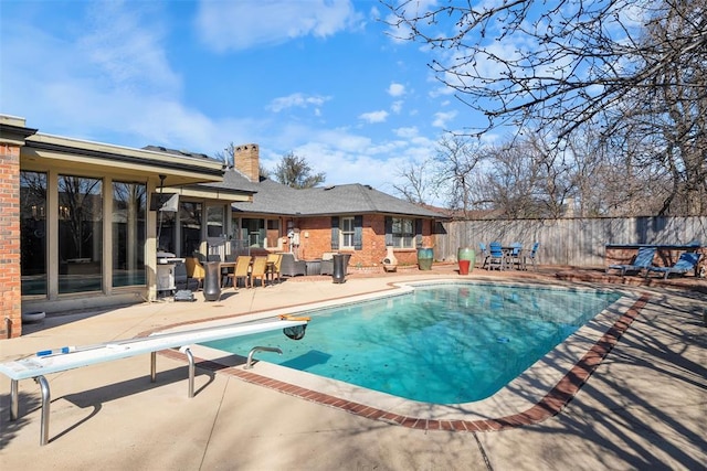 view of swimming pool with a patio, a diving board, fence, and a fenced in pool