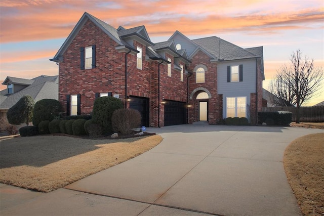 traditional home featuring an attached garage, driveway, and brick siding