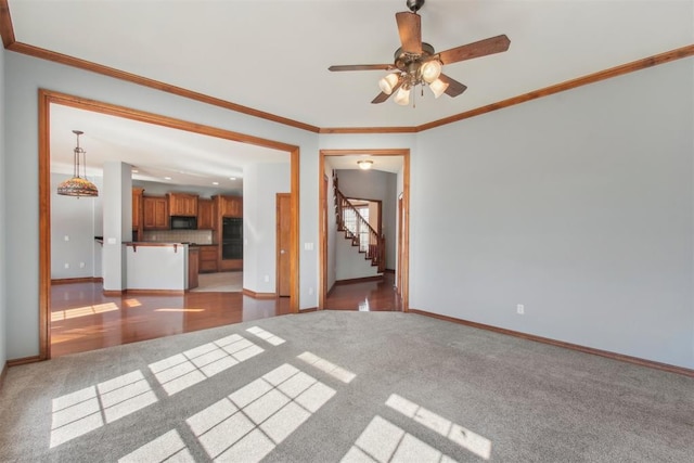 unfurnished living room featuring stairs, baseboards, light colored carpet, and crown molding