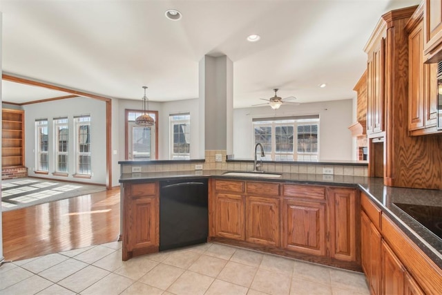 kitchen with brown cabinets, dark countertops, a sink, a peninsula, and black appliances