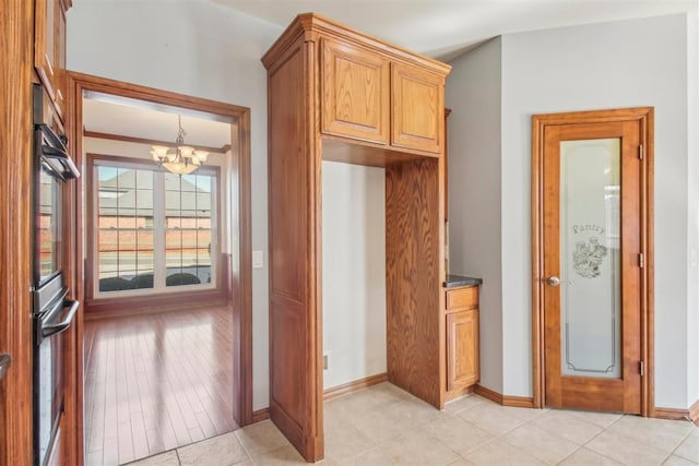 kitchen with double wall oven, dark countertops, a notable chandelier, and baseboards