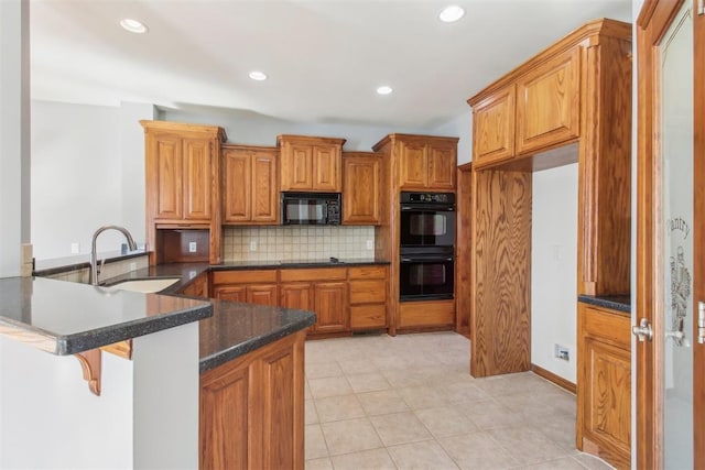 kitchen featuring tasteful backsplash, brown cabinetry, a peninsula, black appliances, and a sink