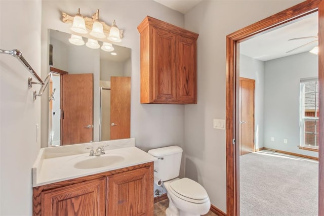 bathroom featuring toilet, baseboards, a ceiling fan, and vanity