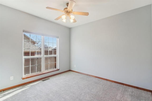 spare room with carpet, visible vents, ceiling fan, and baseboards