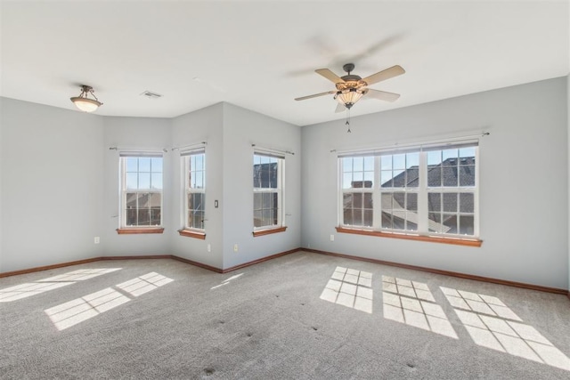 spare room featuring light colored carpet, ceiling fan, visible vents, and baseboards