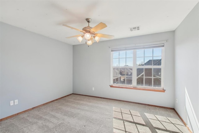 empty room featuring light carpet, a ceiling fan, visible vents, and baseboards