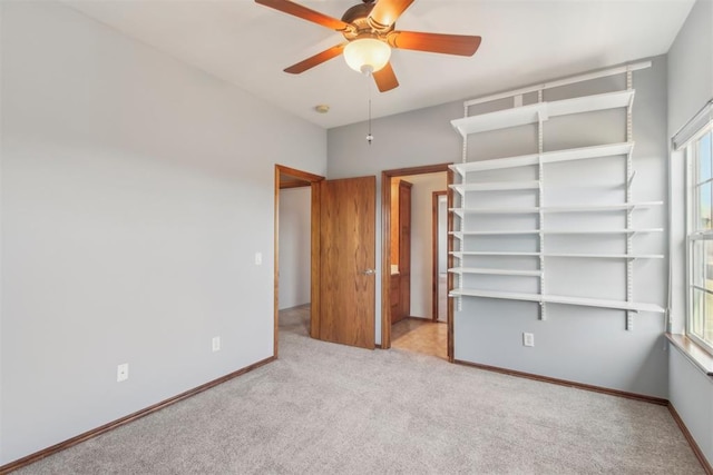 unfurnished bedroom featuring light carpet, a ceiling fan, and baseboards