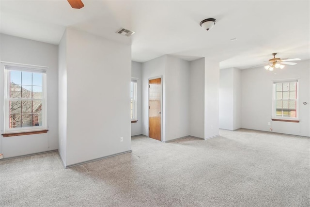 unfurnished room with light carpet, a ceiling fan, visible vents, and a healthy amount of sunlight