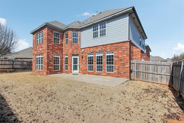 rear view of property featuring brick siding, a patio, and a fenced backyard