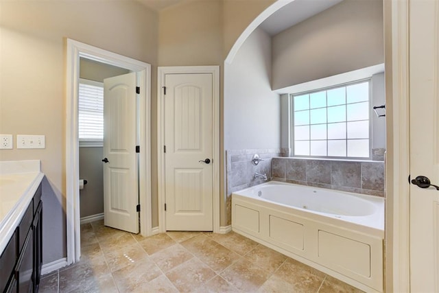 bathroom with baseboards, a bath, and vanity