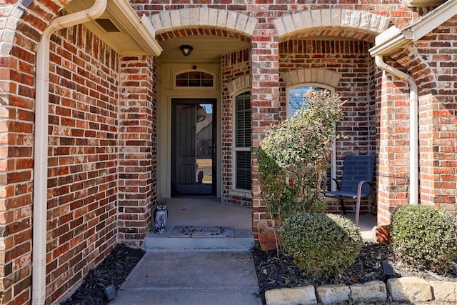 entrance to property with covered porch and brick siding