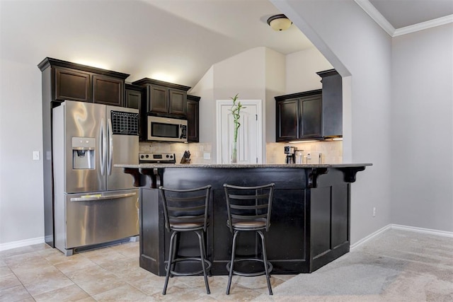 kitchen with tasteful backsplash, arched walkways, appliances with stainless steel finishes, a kitchen breakfast bar, and ornamental molding