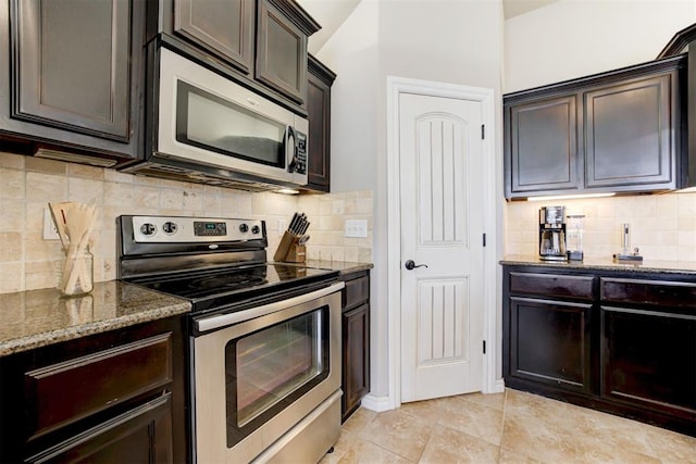 kitchen featuring stainless steel appliances, decorative backsplash, dark stone countertops, and dark brown cabinets