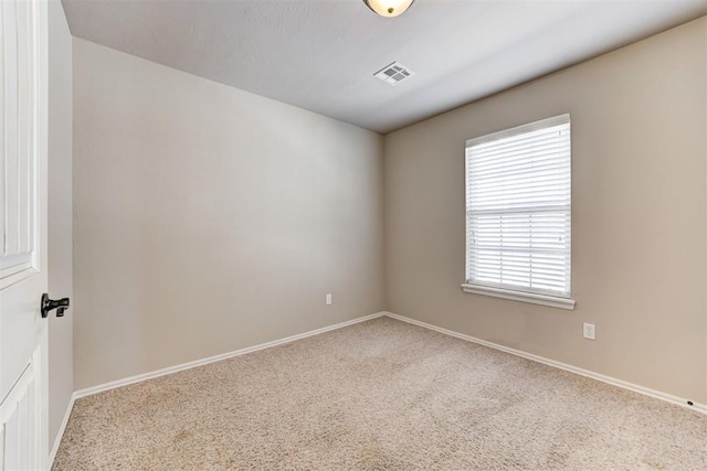 carpeted spare room with visible vents and baseboards